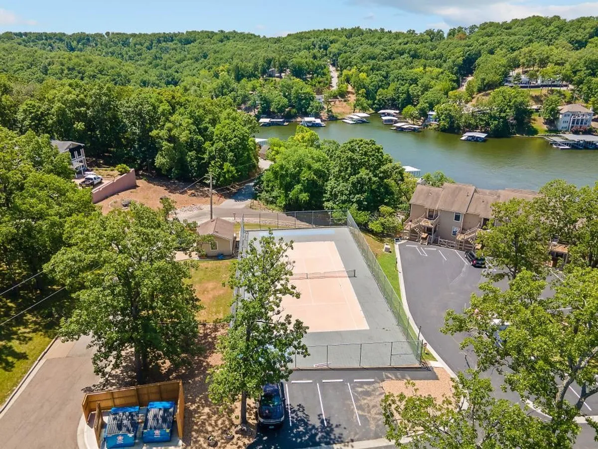 An outdoor sports court set amid lush greenery and a distant water view, this image highlights the multi-purpose court where basketball or tennis can be enjoyed. The surrounding park-like area suggests additional space for picnics and relaxed gatherings.