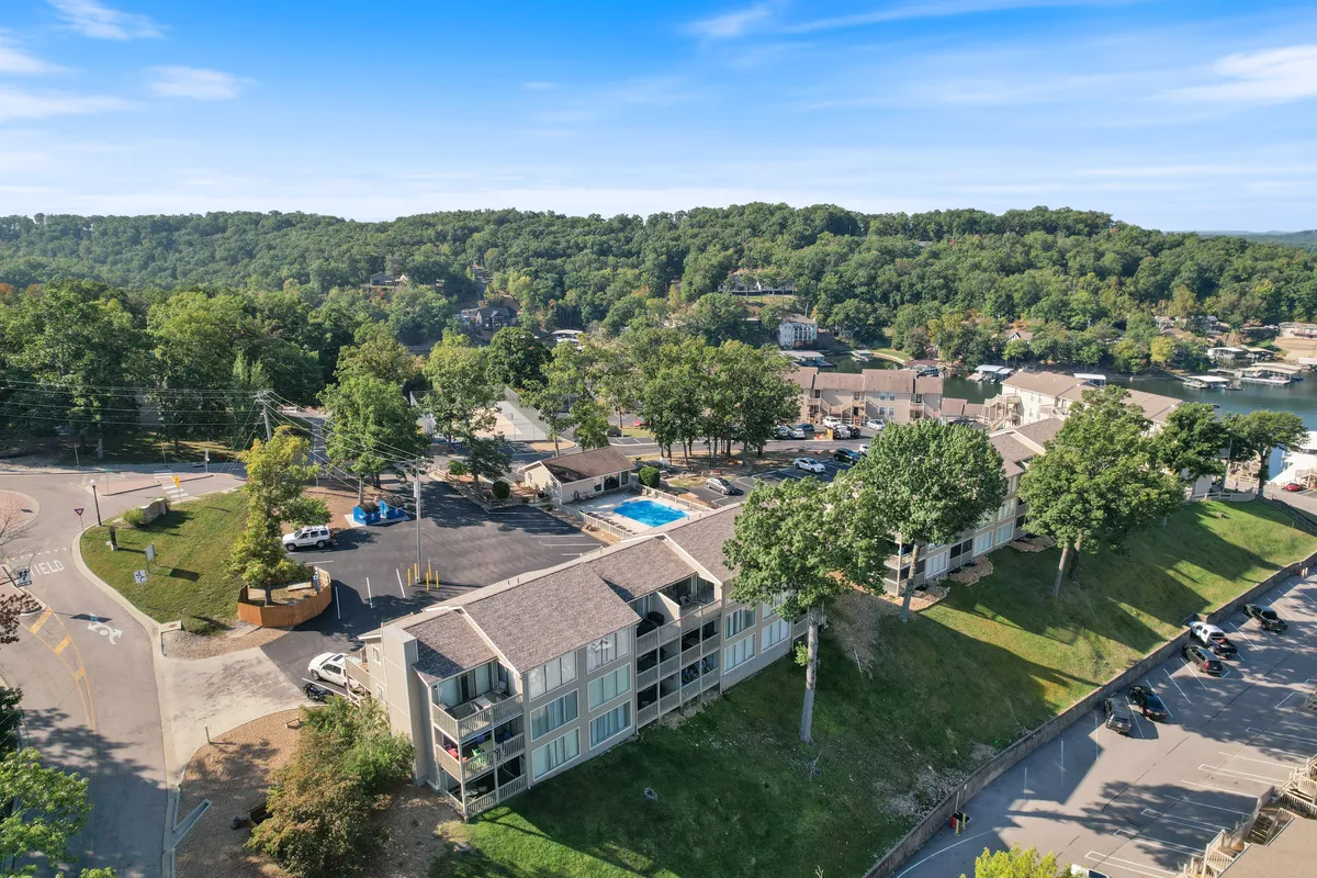 A view of another community swimming pool nestled among green landscaping and adjacent buildings, creating a recreational environment for socializing and fun outdoor activities.