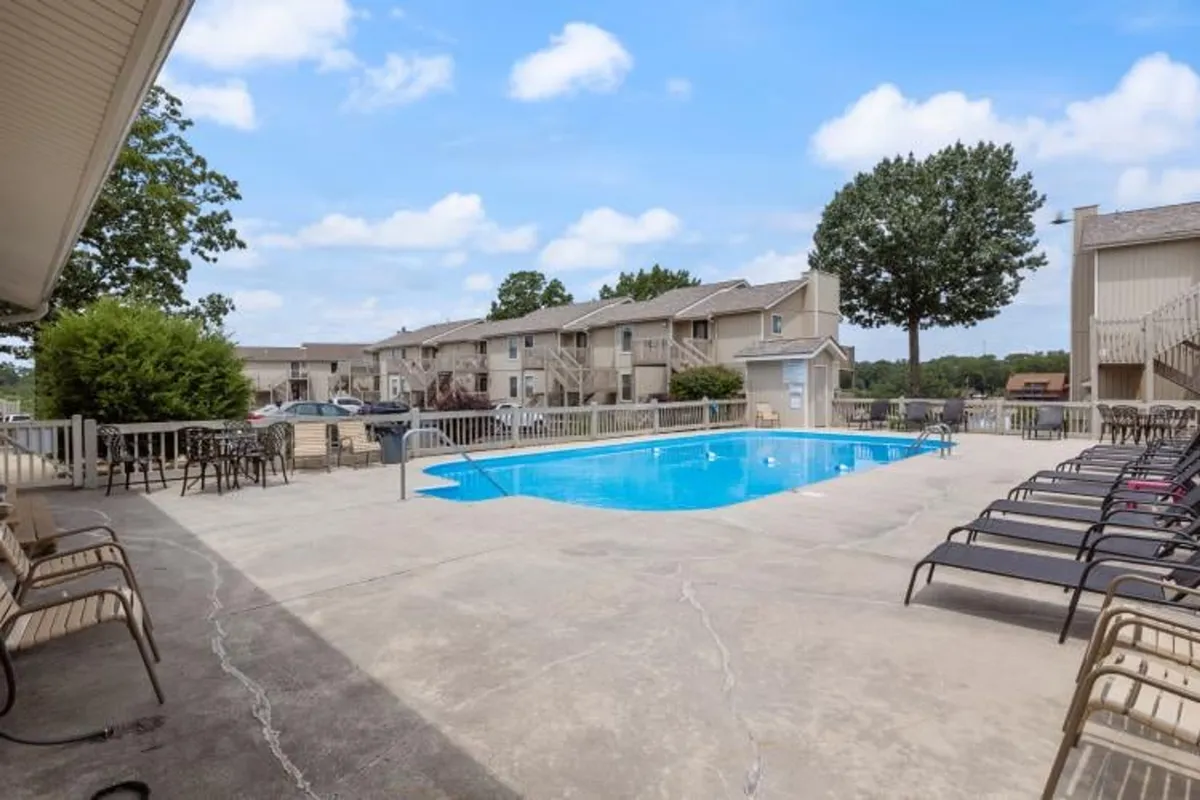 This image displays a sparkling community swimming pool surrounded by inviting lounge chairs and lush greenery. The relaxed atmosphere is perfect for families and children who want to enjoy sunny days swimming or relaxing by the water.