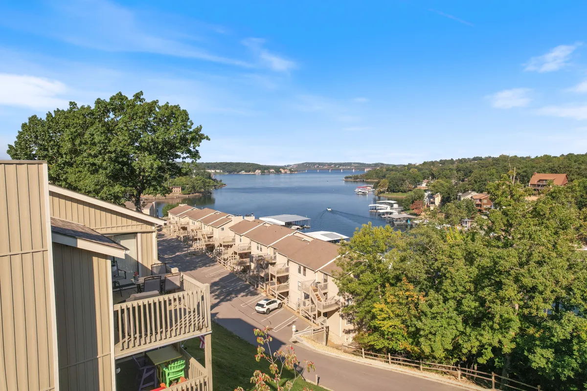 A scenic lake view with houses along the shore, lush greenery, and a clear blue sky. The tranquil setting is ideal for boating, fishing, and lakeside walks—activities highlighted in the section.