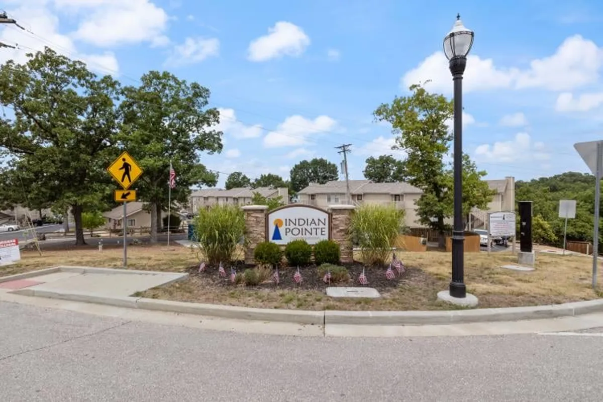 A welcoming exterior view featuring the Indian Pointe sign, attractive landscaping, and a street lamp, evoking a sense of arrival and community spirit. The scene hints at community events and neighborhood gatherings.