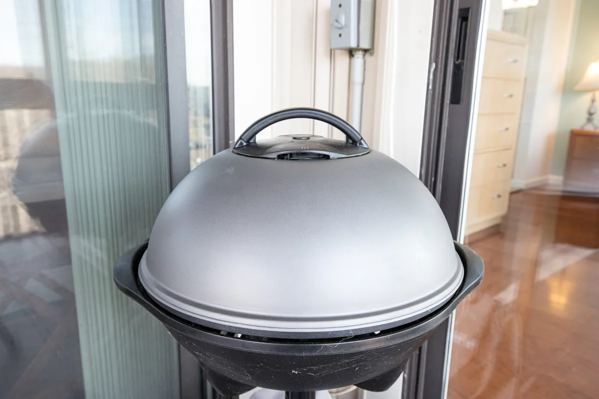 A close-up of a grill situated on a patio, set up for outdoor cooking and gatherings. The relaxed setup invites guests to imagine family barbecues or group meals with a scenic backdrop.